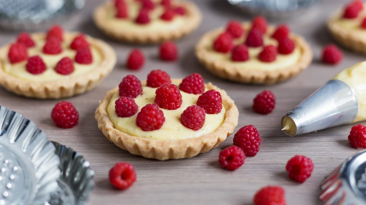 Home-made custard tarts decorated with freshly picked raspberries