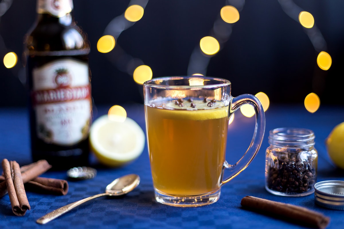 Grzane piwo with its ingredients in the background with fairy lights.