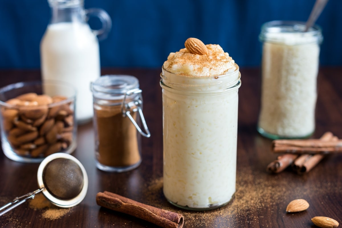 Risgrynsgröt in a serving jar surrounded by ingredients and decorations.