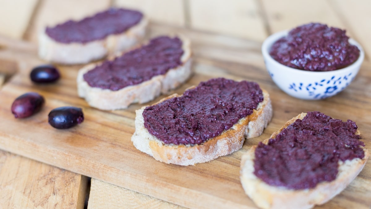 Black olive paté, or black olive paste, spread on bread is one of those lovely alternatives to the classic garlic and tomato bruchetta topping.