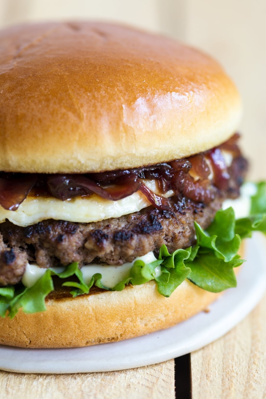 Closeup of a hamburger with caramelized onion relish, grilled halloumi, beef patty, mayonnaise and lettuce.