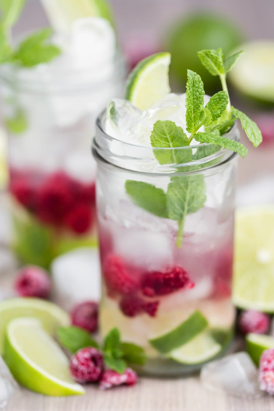 Two glasses of coconut water mojito with frozen raspberries.