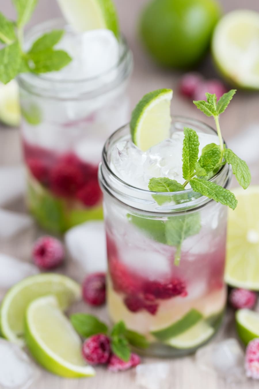 Two glasses of coconut water mojito with frozen raspberries.