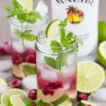 Two glasses of coconut water mojito with frozen raspberries; Malibu coconut rum bottle in the background.