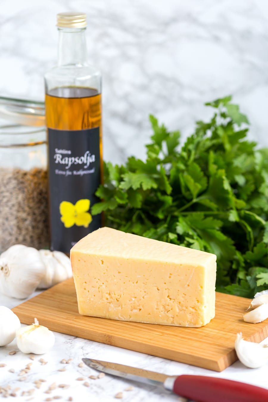 Västerbotten cheese on a tray, fresh basil and rape seed oil in the background.