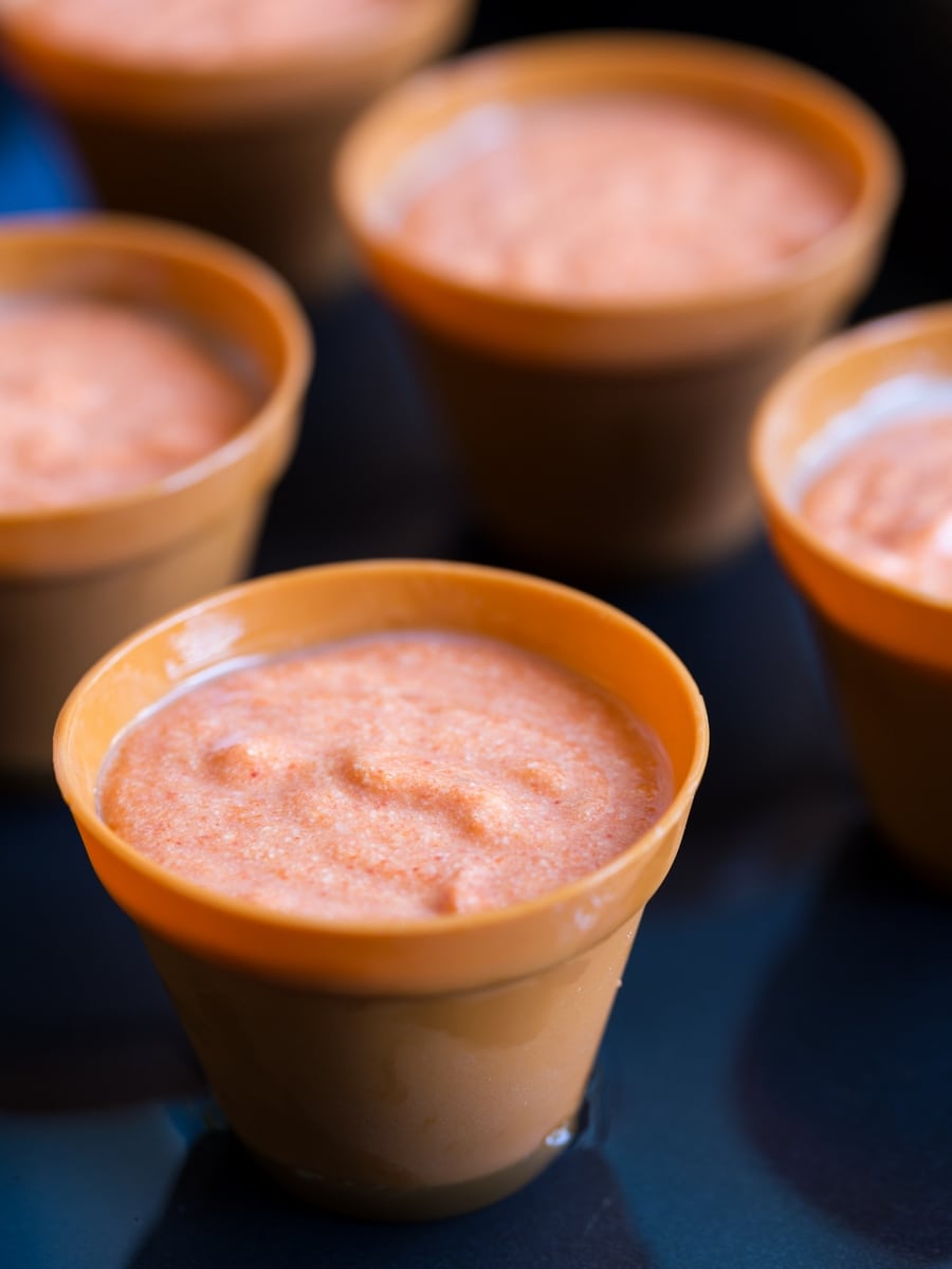 Red pepper flan batter in moulds, in a water bath.