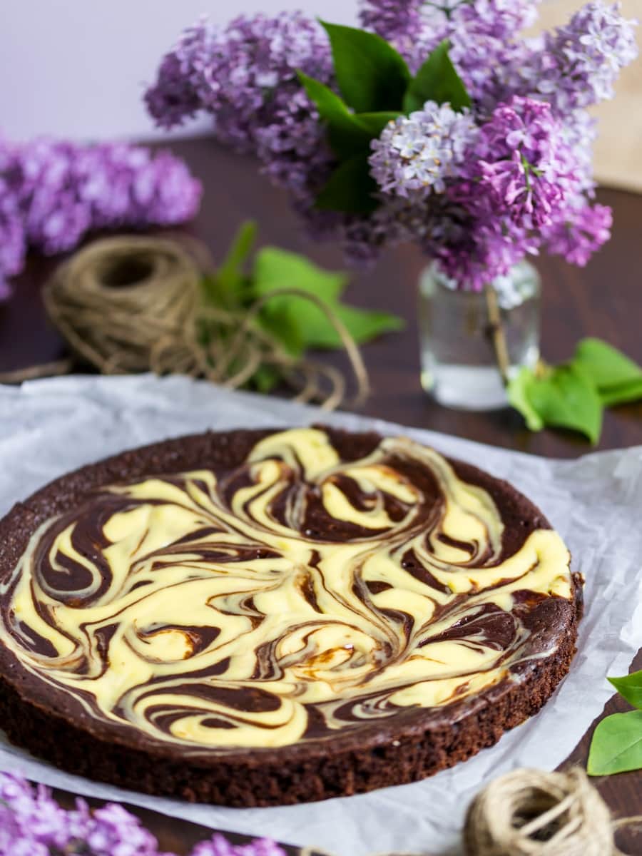 Chocolate cake with a cream cheese swirl, flowers in the background.