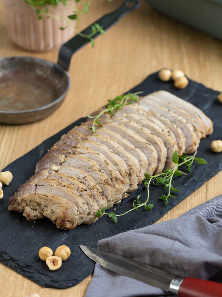 Sliced baked pork loin on black plate.