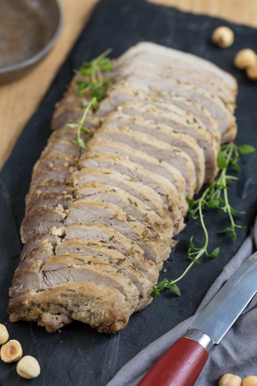Sliced oven-baked pork loin decorated with fresh thyme leaves.