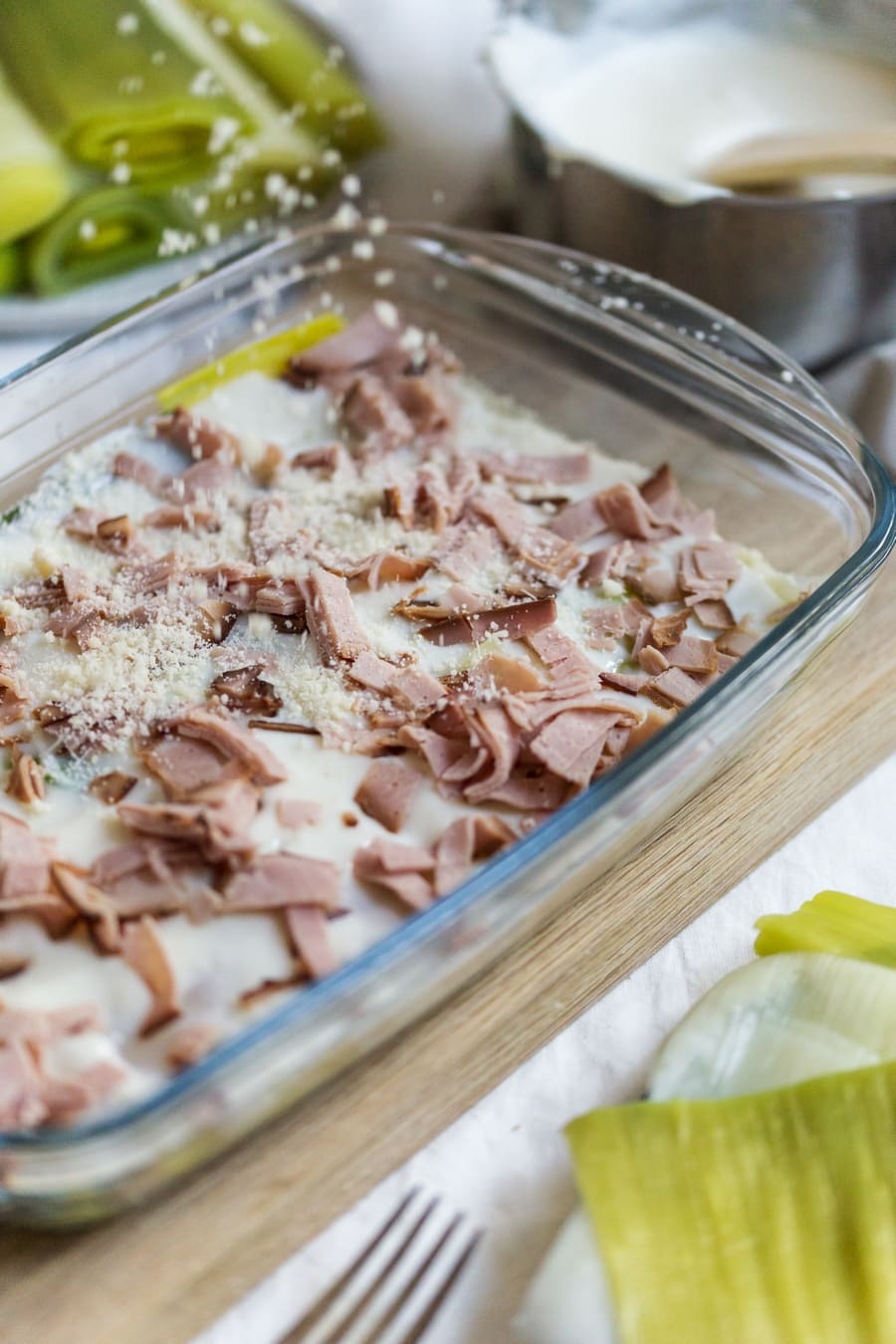 Assembling the leek lasagna in the casserole dish. Parmesan being sprinkled over.