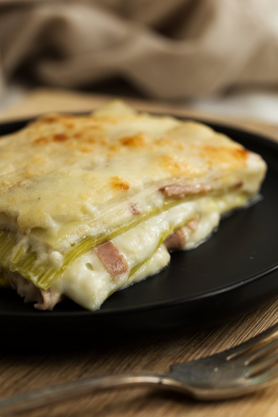 Leek lasagne on black plate, portioned.