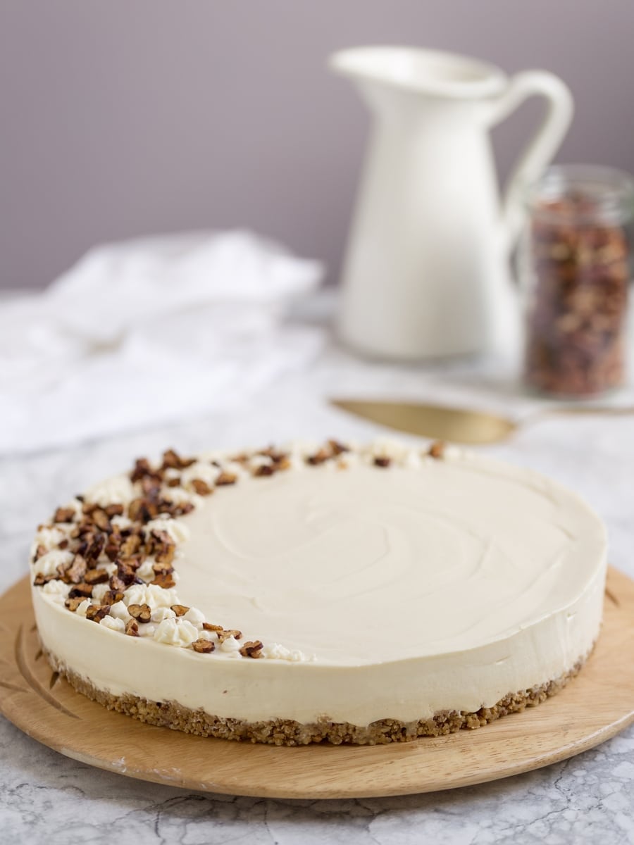 No-bake maple cheesecake on wooden tray, obejcts in the background.