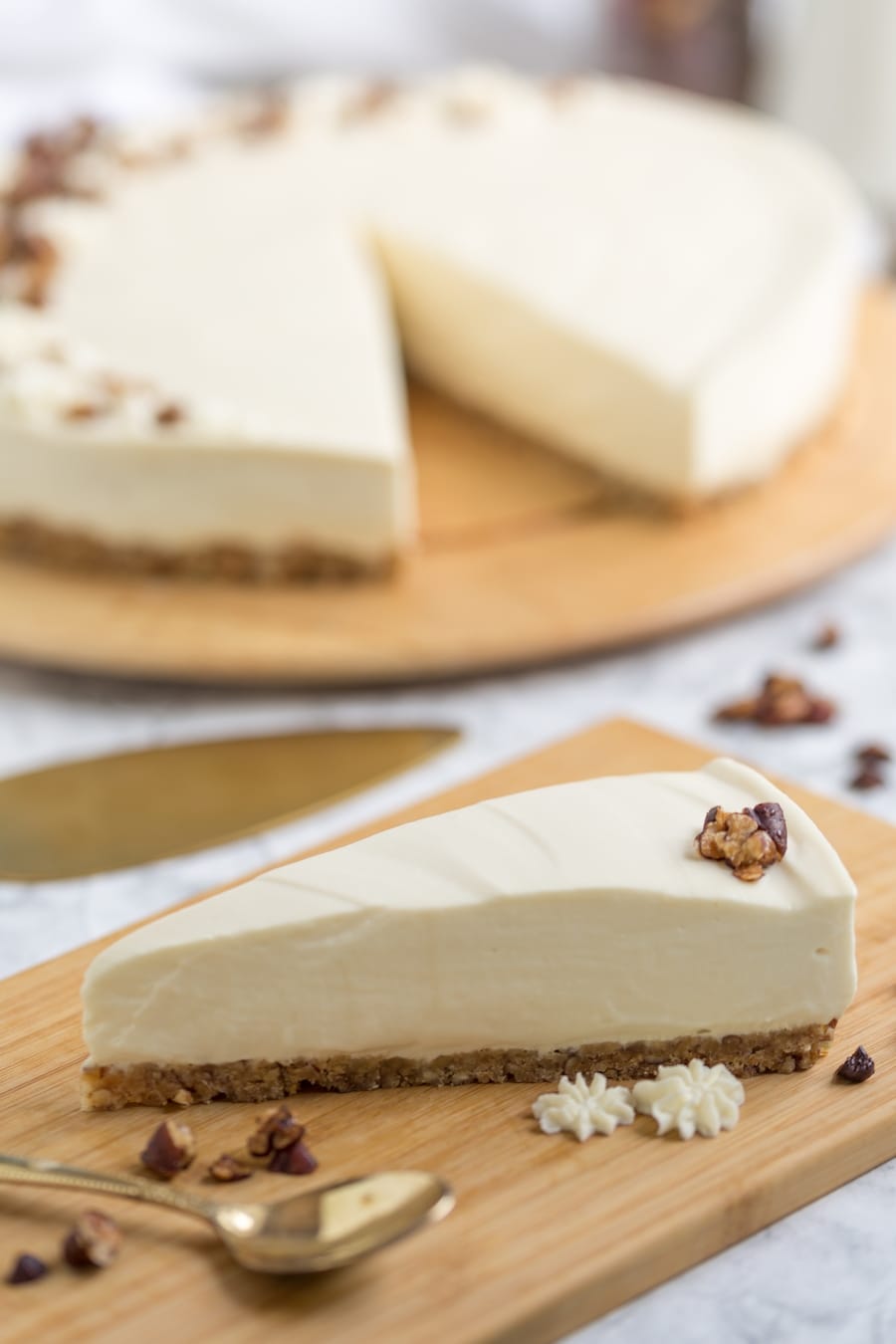 Slice of cheesecake with rest of cake in the background.