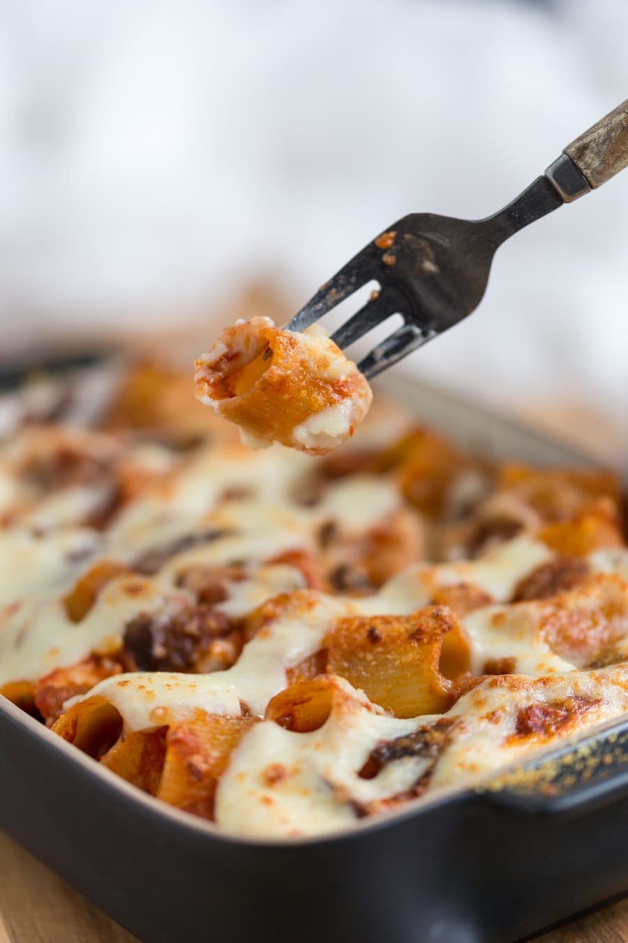 Fork lifting pasta piece from baked pasta casserole.