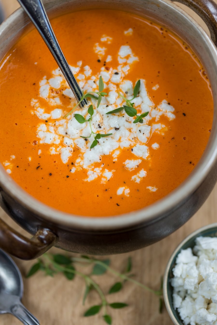 Flatlay closeup of goat cheese crumbled over orange coloured soup.