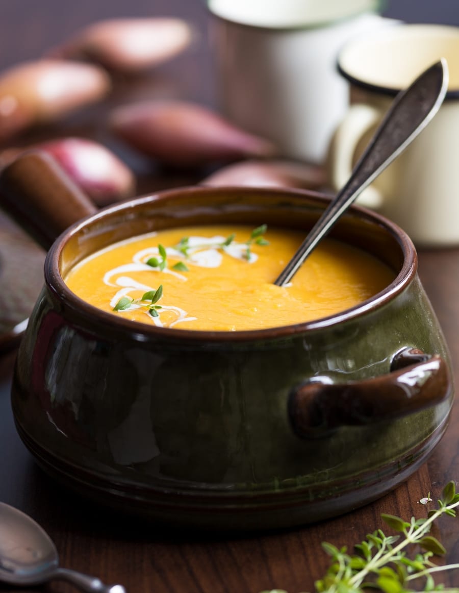 Ceramic pot filled with an orange soup, ladle sticking out.