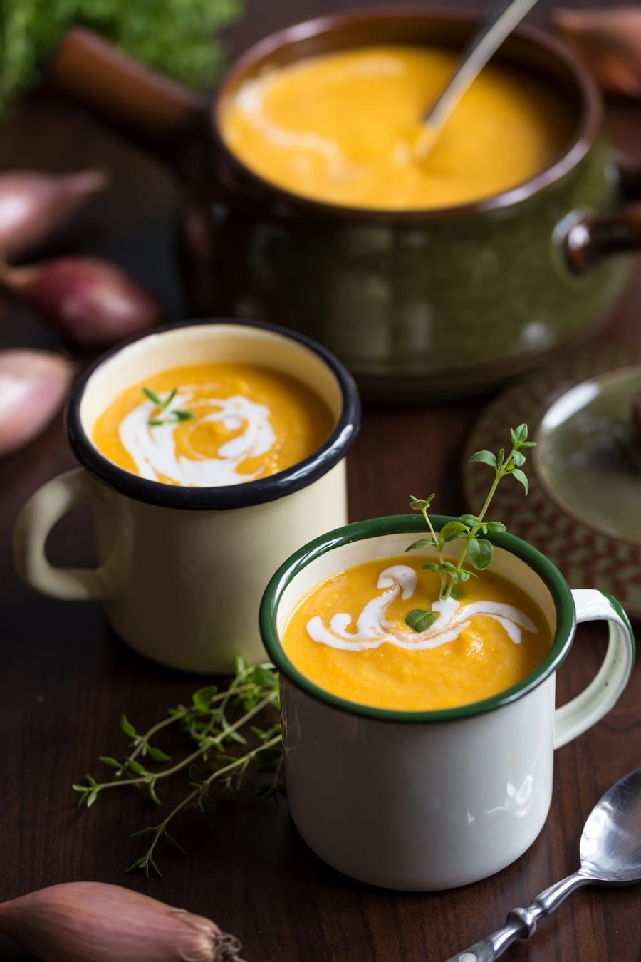Roasted pumpkin and red lentil soup in enamel mugs, decorated with fresh thyme.