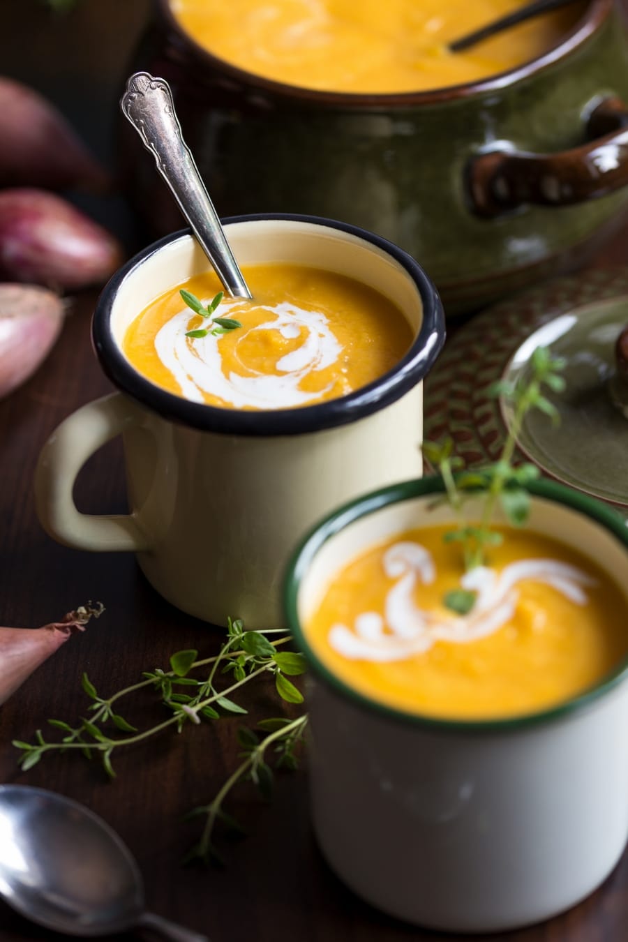 Roasted pumpkin and red lentil soup in enamel mugs, decorated with fresh thyme.