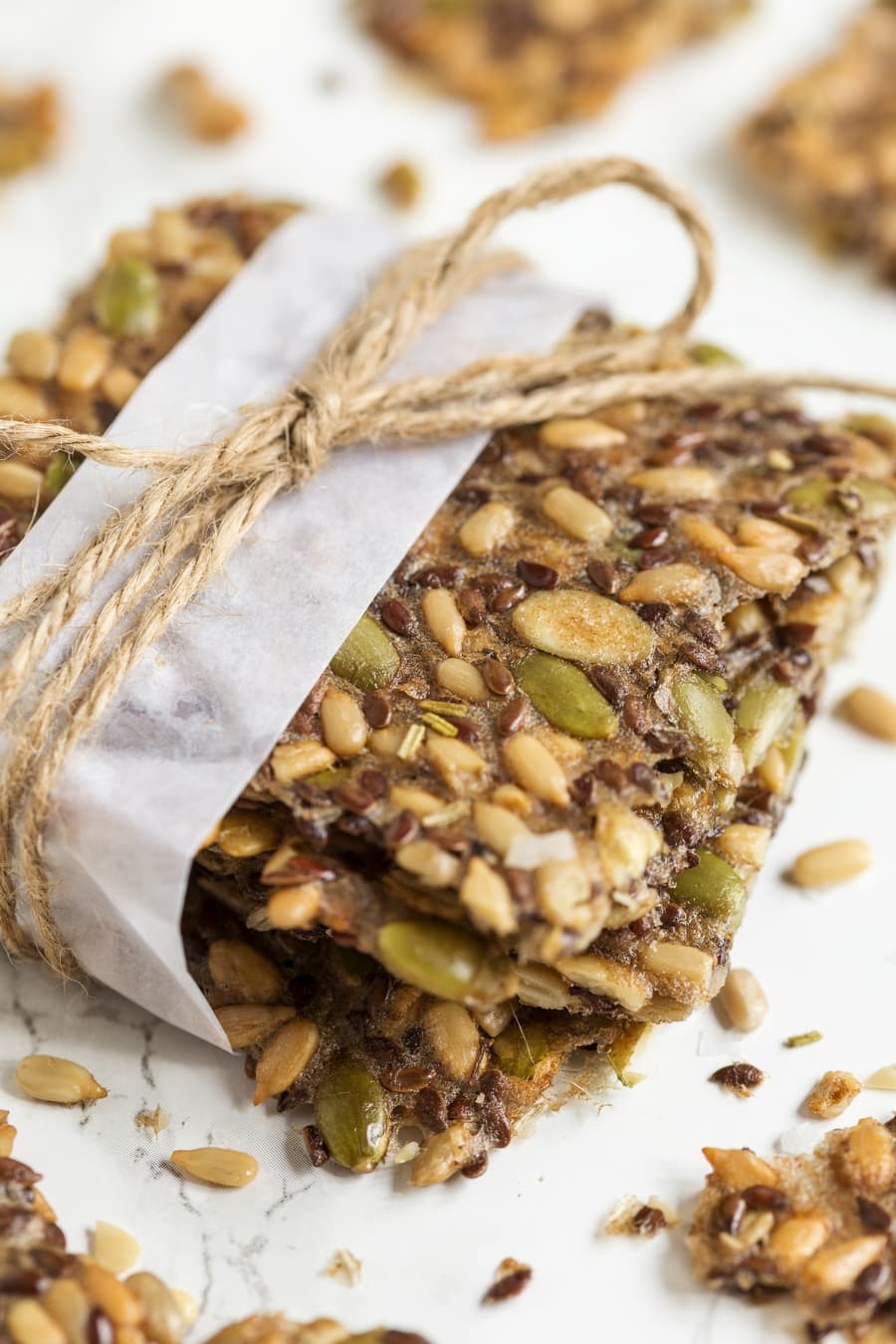 Homemade seed crackers, wrapped with white paper and jute twine.