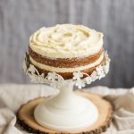 Frosted sweet potato cake on white cake stand.