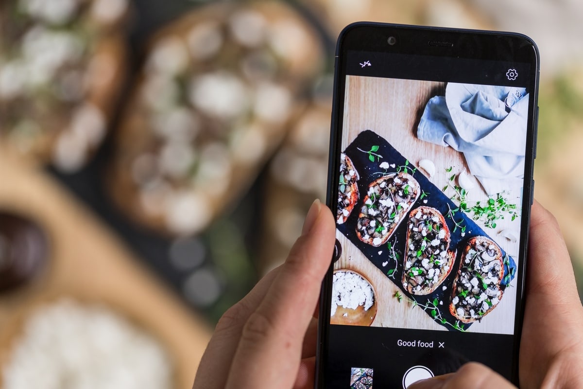 Phone photographing food in the background.