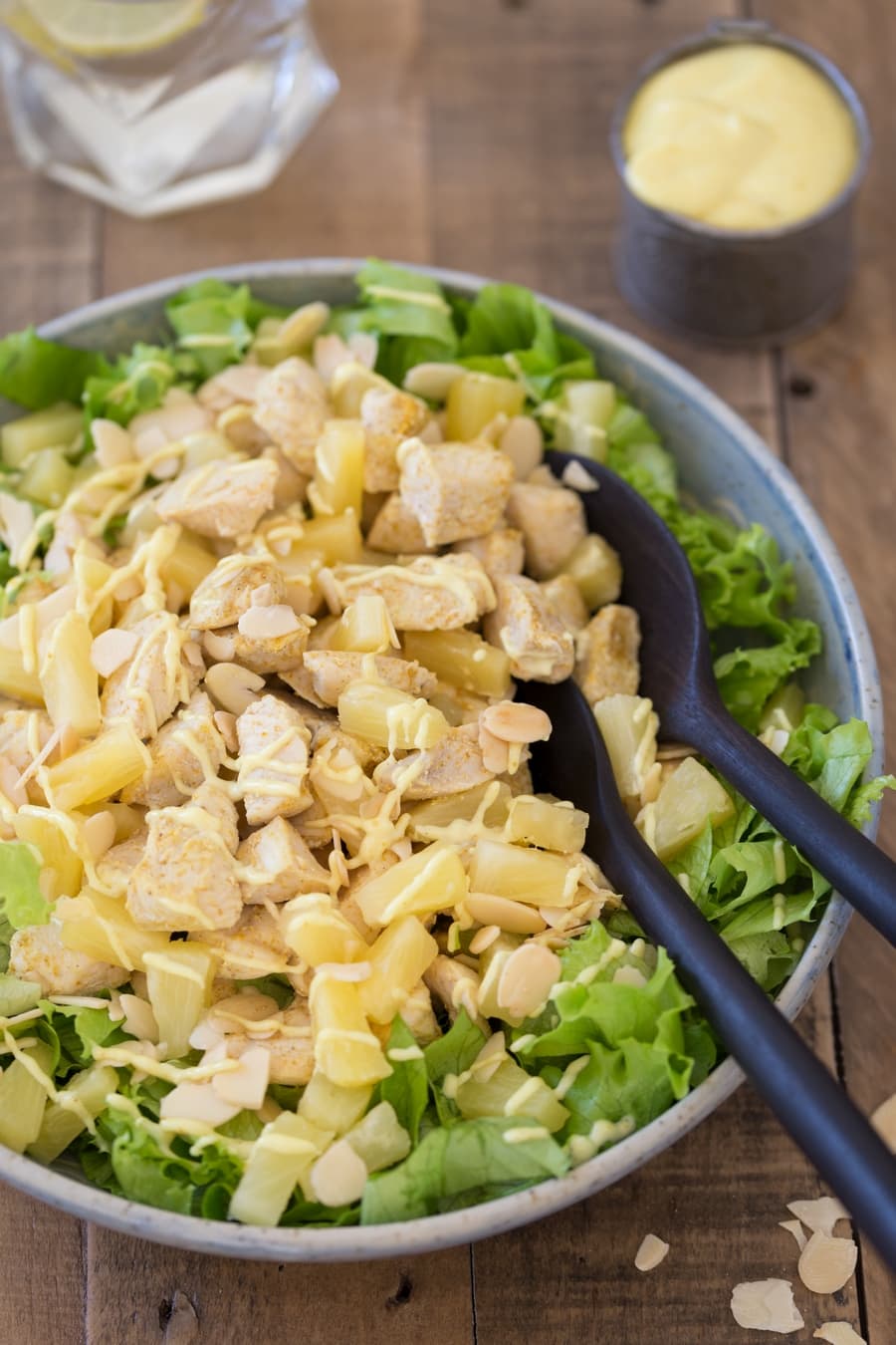 Chicken pineapple salad with salad serving spoons in a blue bowl.