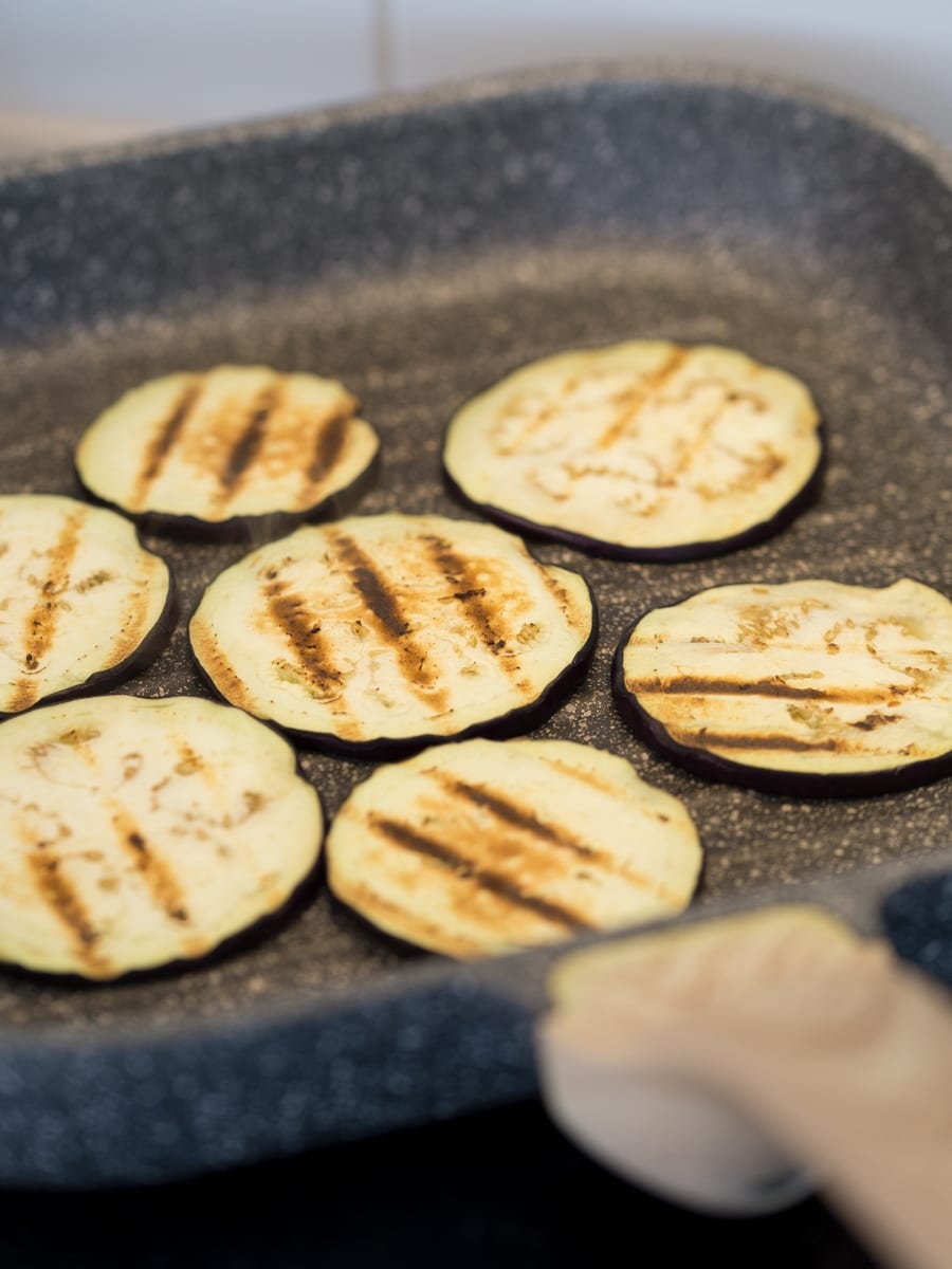 Eggplant slices in a grill skillet on the stove.