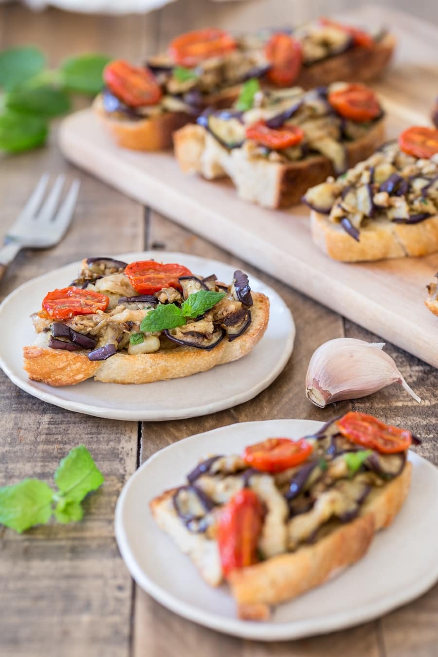 Slices of toasted bread topped with grilled eggplants and roasted cherry tomatoes.