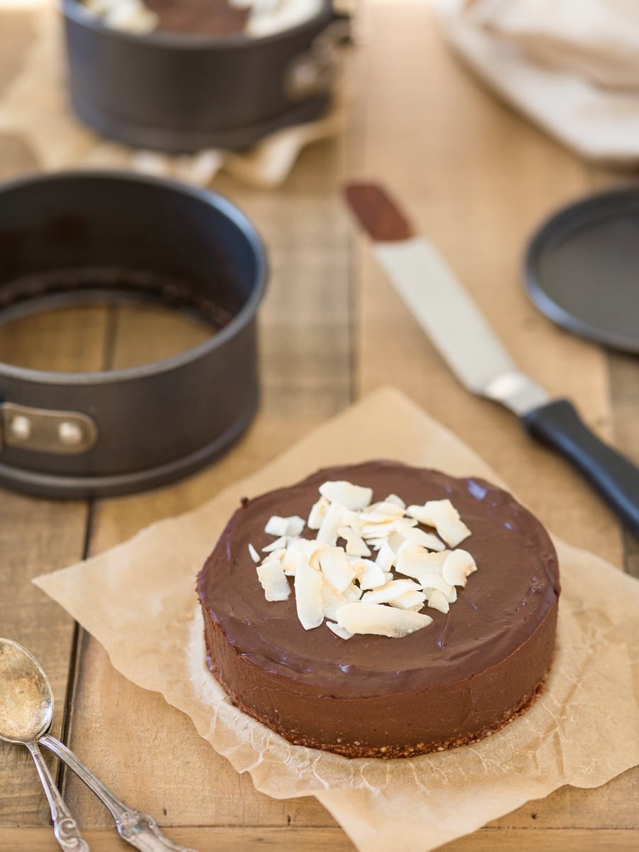 Small chocolate cake out of springform pan, dirty spatula on the right.