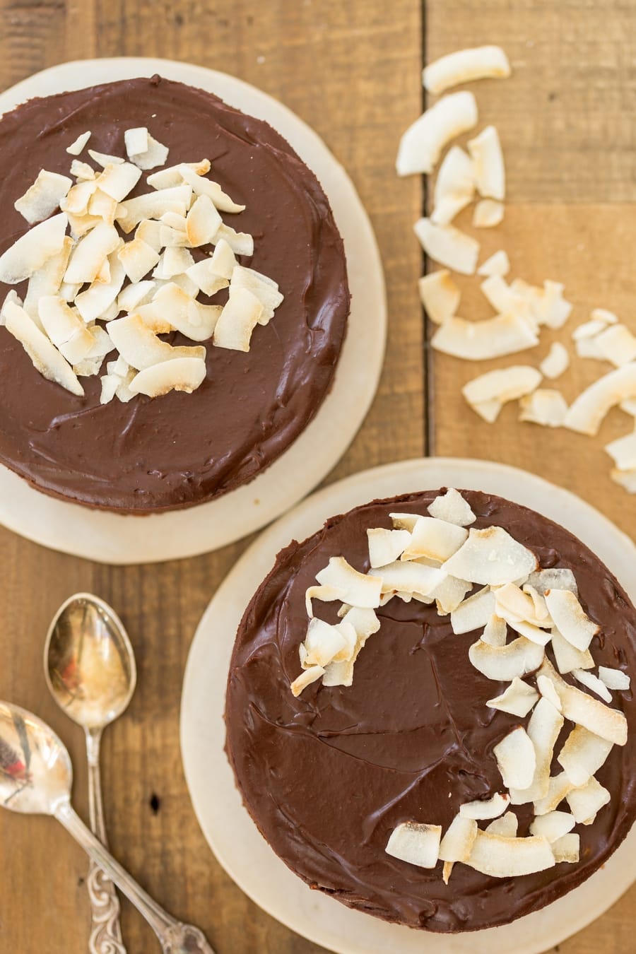 Vegan chocolate cake with toasted coconut flakes on simple white plates.