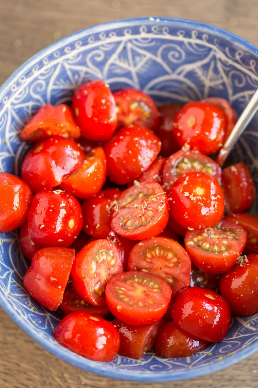 Seasoned cherry tomatoes in a blue bowl.