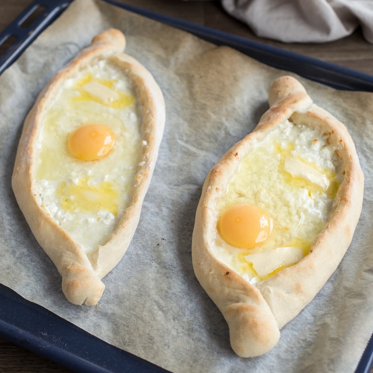 A raw egg is placed on top of baked khachapuri adjaruli.