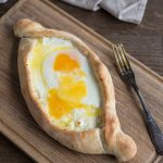 Fully baked adjaruli khachapuri with raw egg yolk on top.
