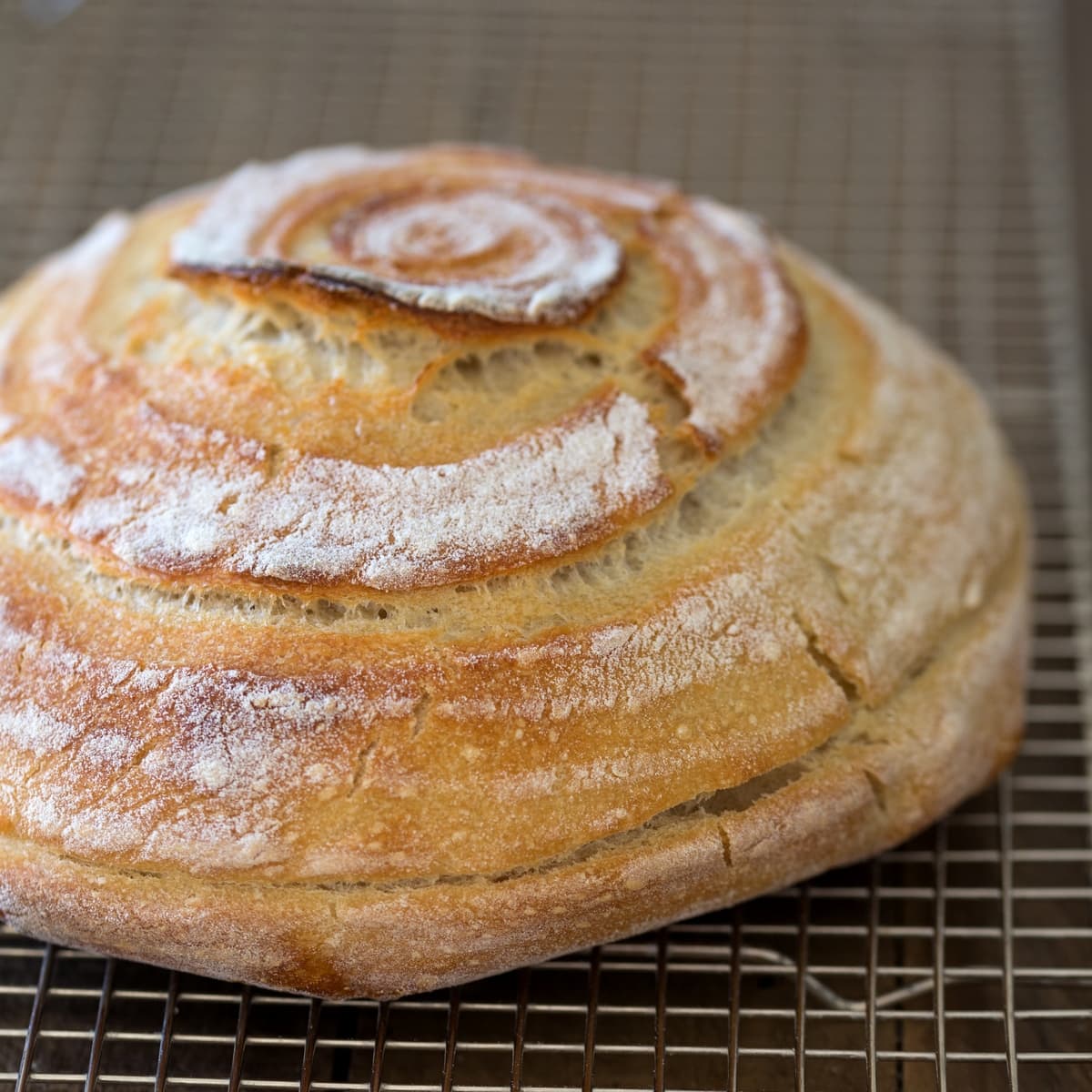A loaf of homemade sourdough bread on cooling rack.
