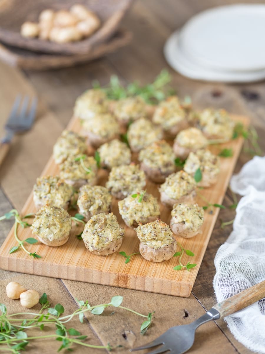 Vegetarian stuffed mushrooms with cream cheese and hazelnut on a bamboo tray.