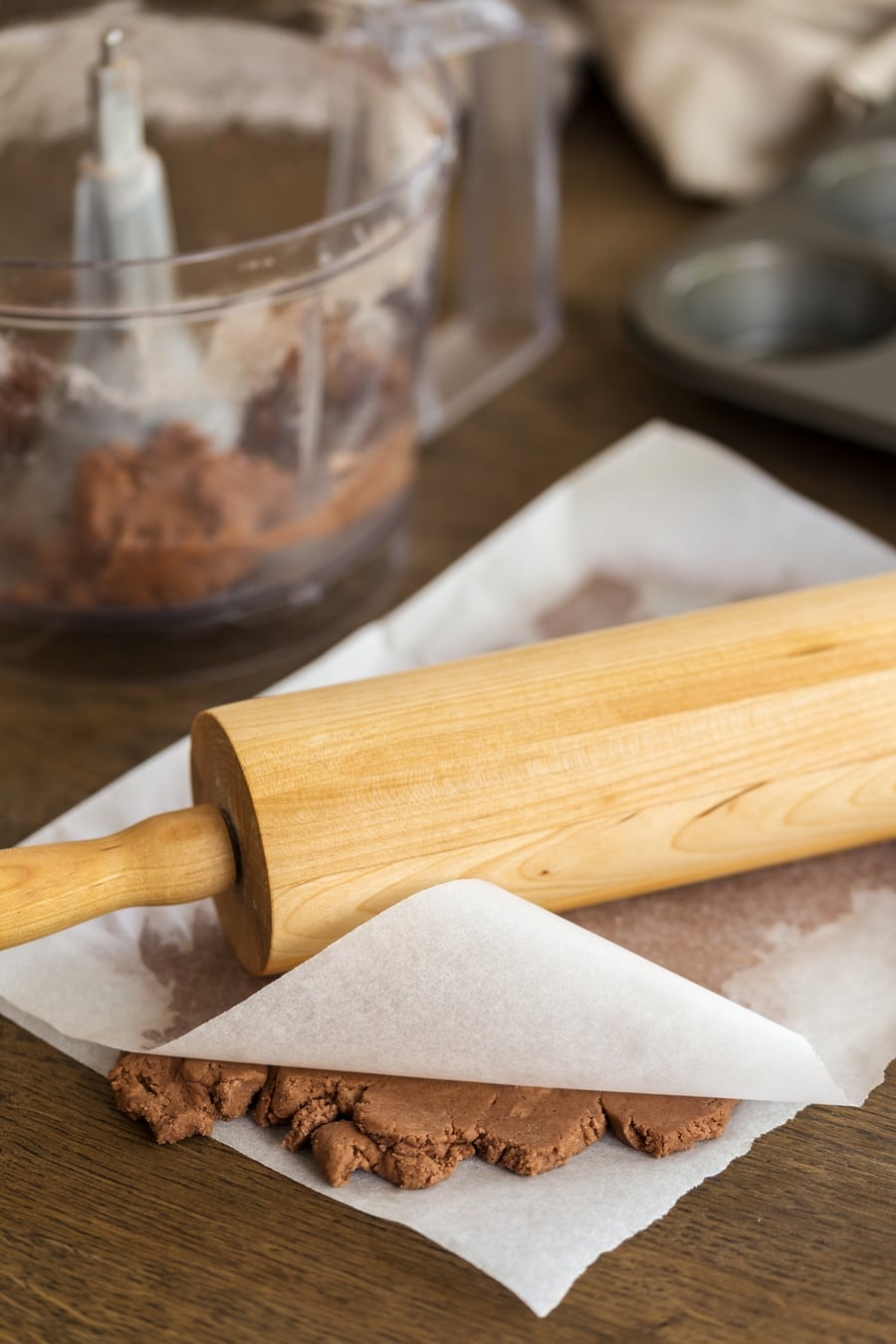 Shortcrust pastry being rolled between two layers of paper.