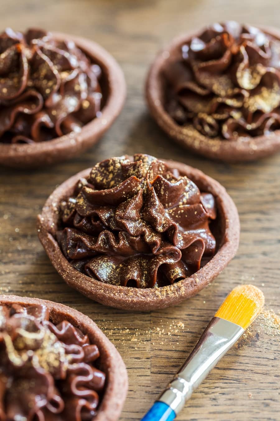Mascarpone chocolate cream tarts decorated with gold glitter.
