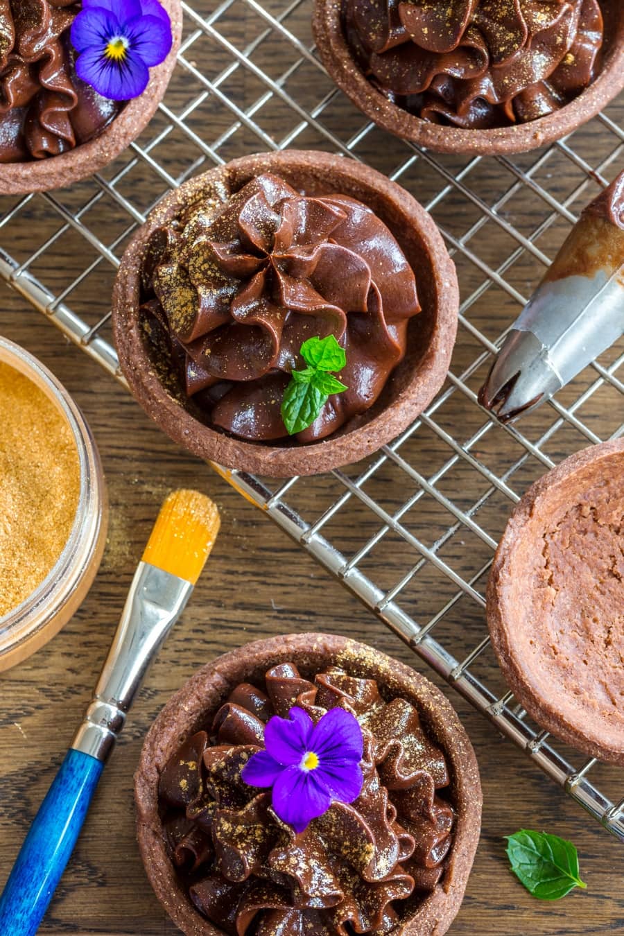 Chocolate mascarpone cream tarts decorated with flowers and edible gold.