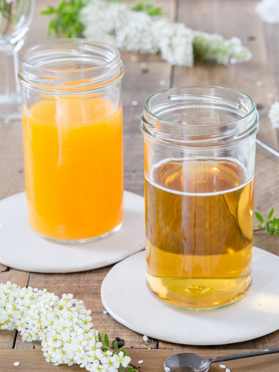 A glass full of apple cider and one full of mango juice.