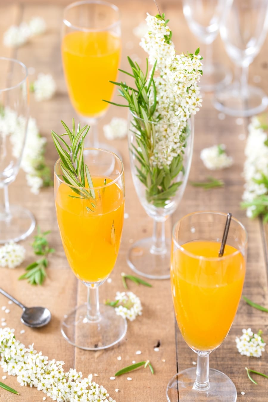 Several flutes with mango cider bellini and flowers.
