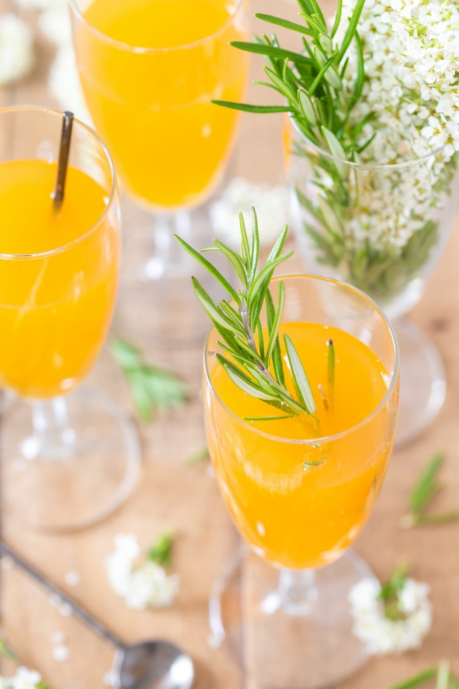Mango cider bellini in flutes, served with rosemary sprig.