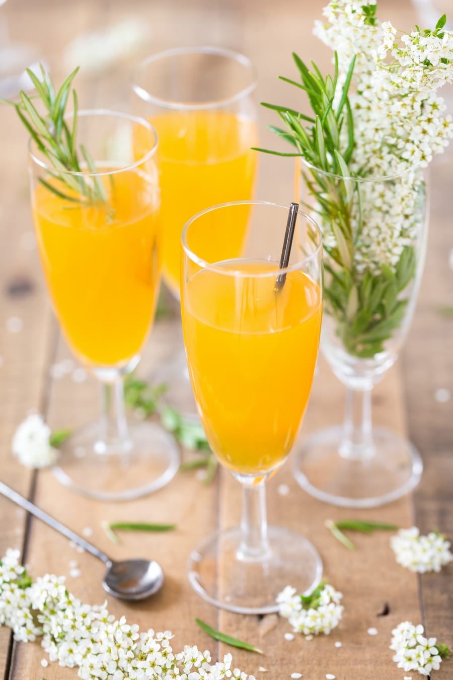 Three champagne glasses with mango cider bellini cocktail.