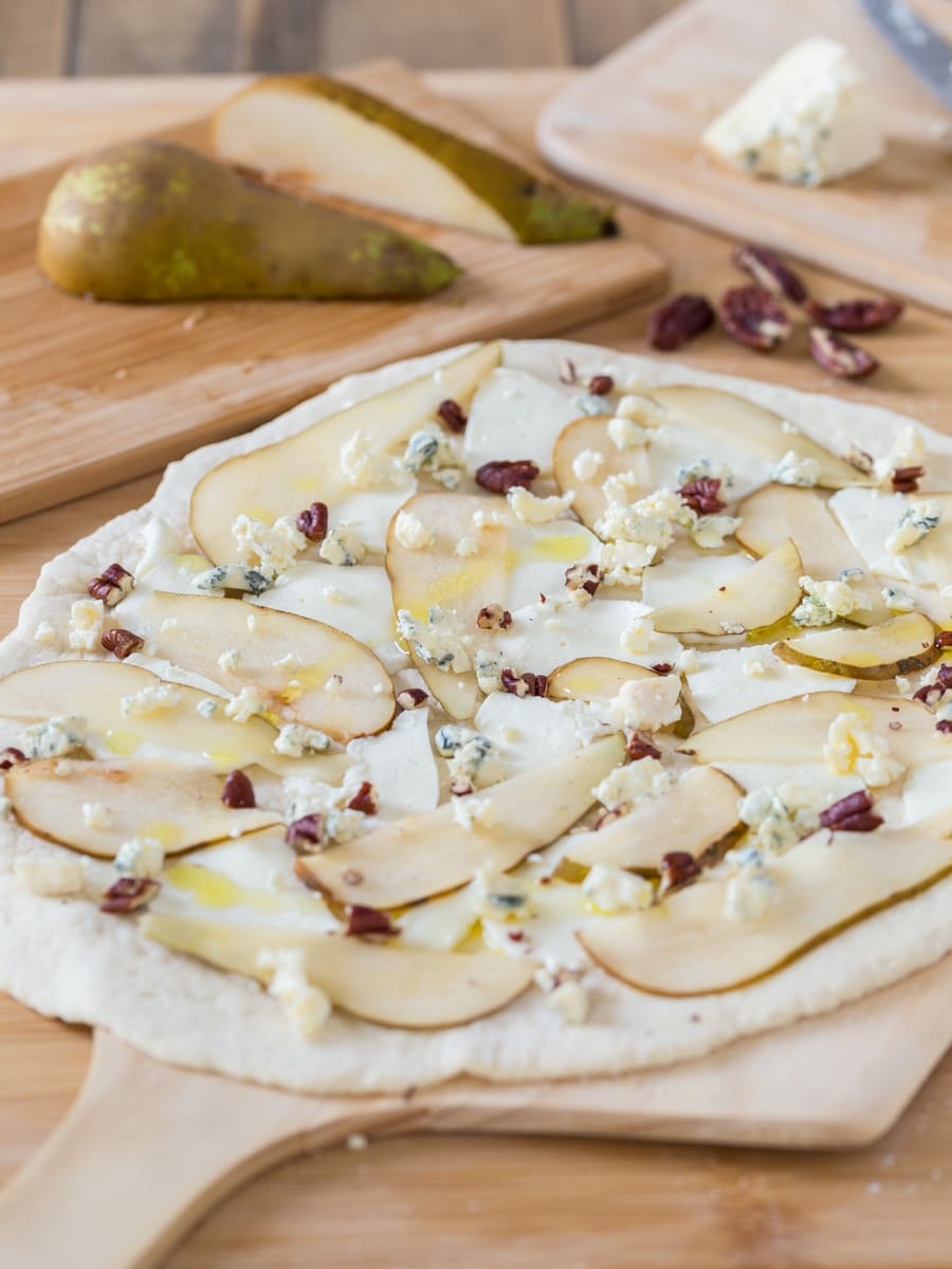 Uncooked pear and blue cheese pizza on a pizza peel.