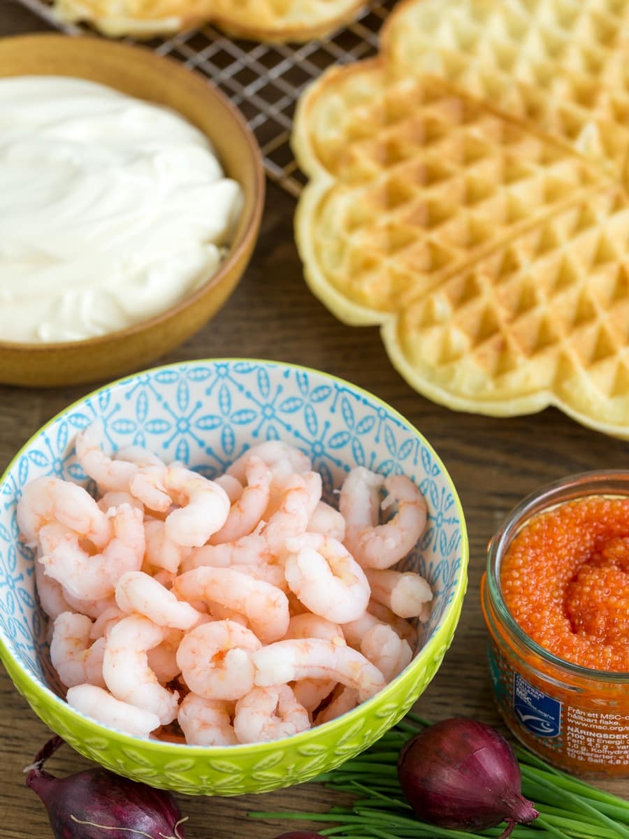Sour cream waffles with shrimp ingredients: shrimps, roe, creme fraiche, red onion and chives.