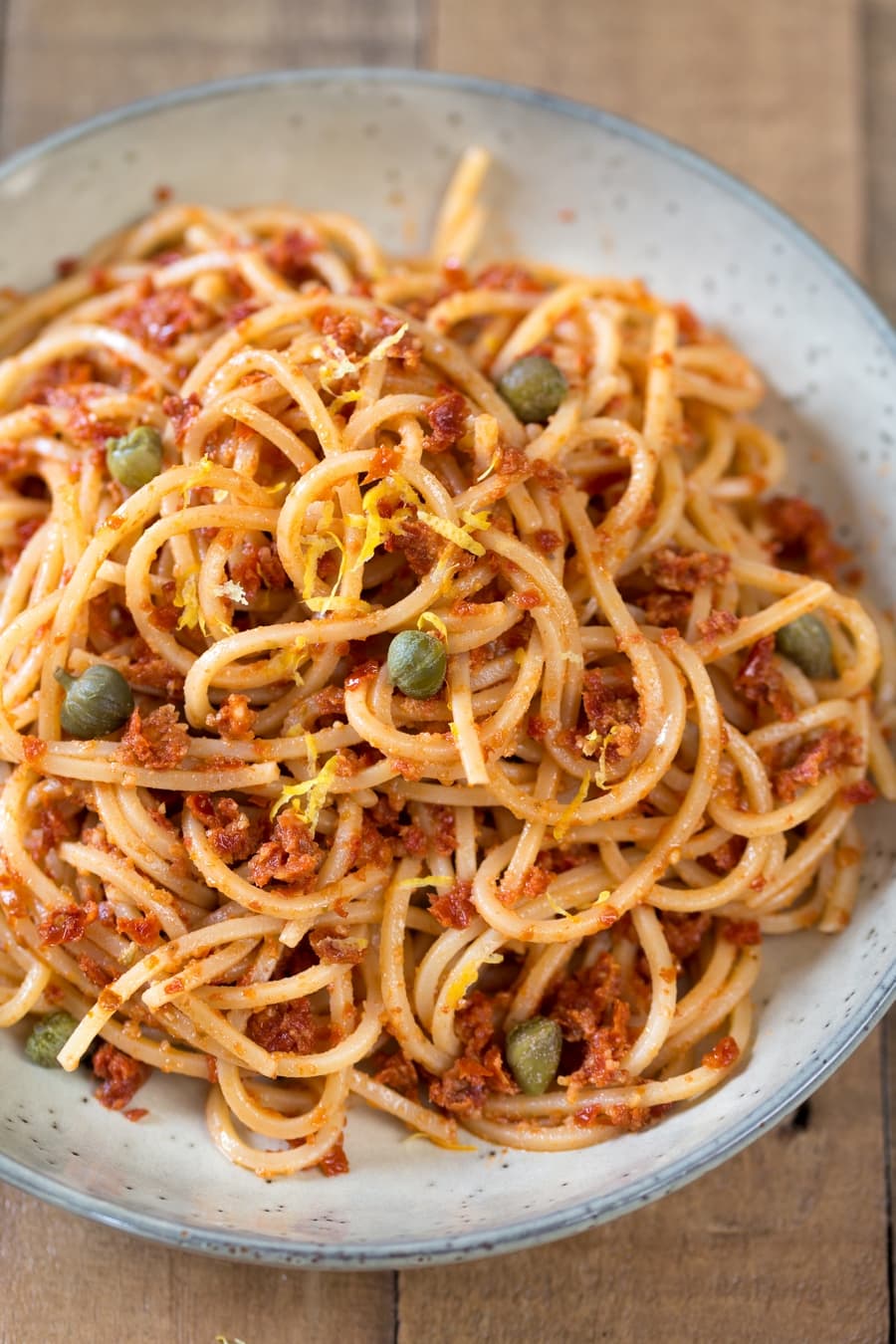 Spaghetti with sun-dried tomato pesto sauce with capers and lemon zest.