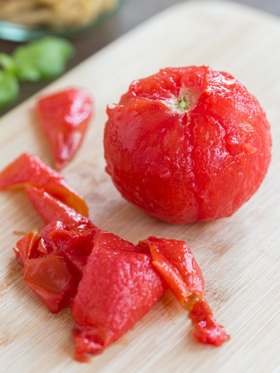 Peeled tomato on wooden cutting board.