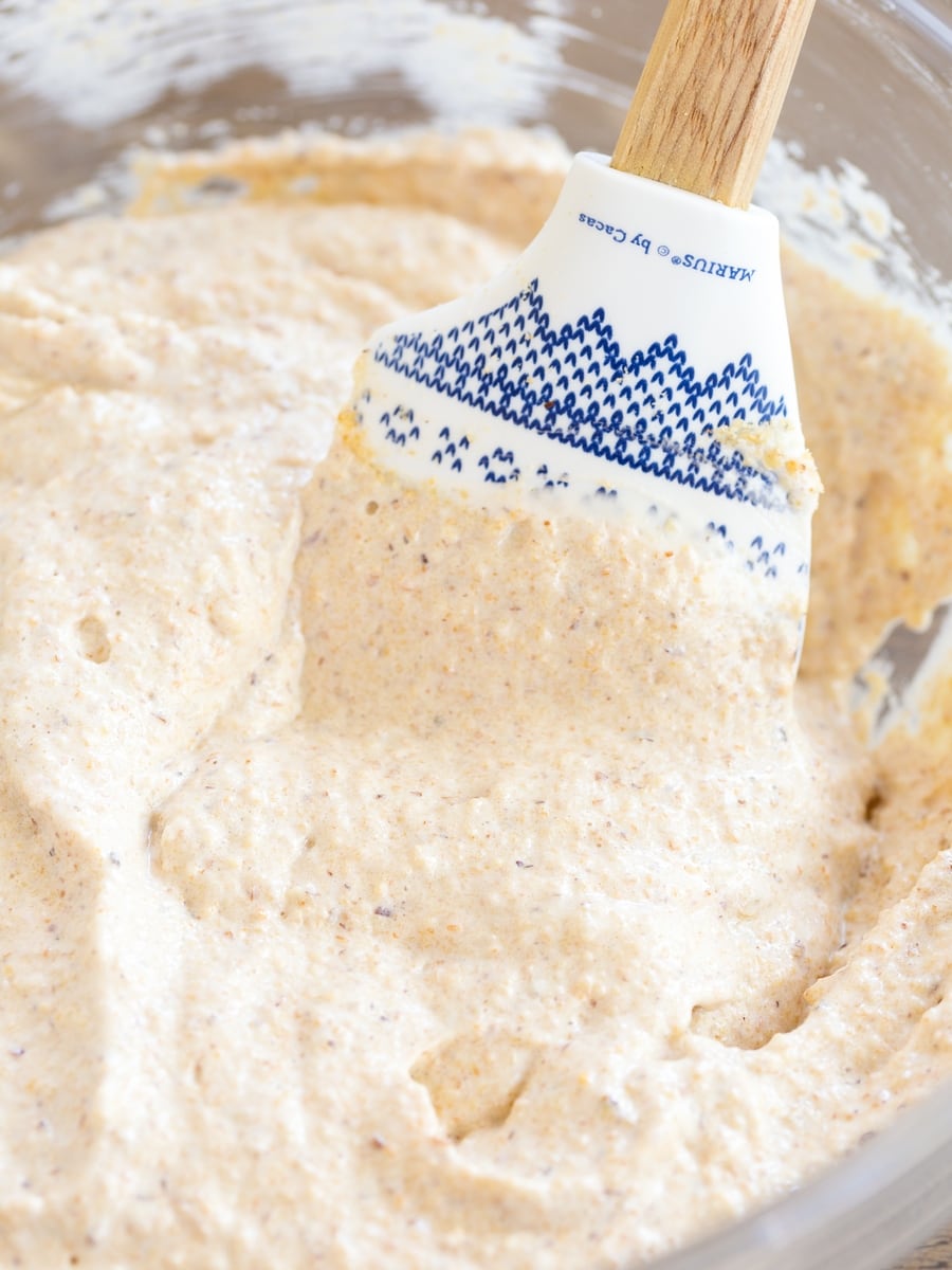 Spatula in bowl with honey hazelnut meringue.