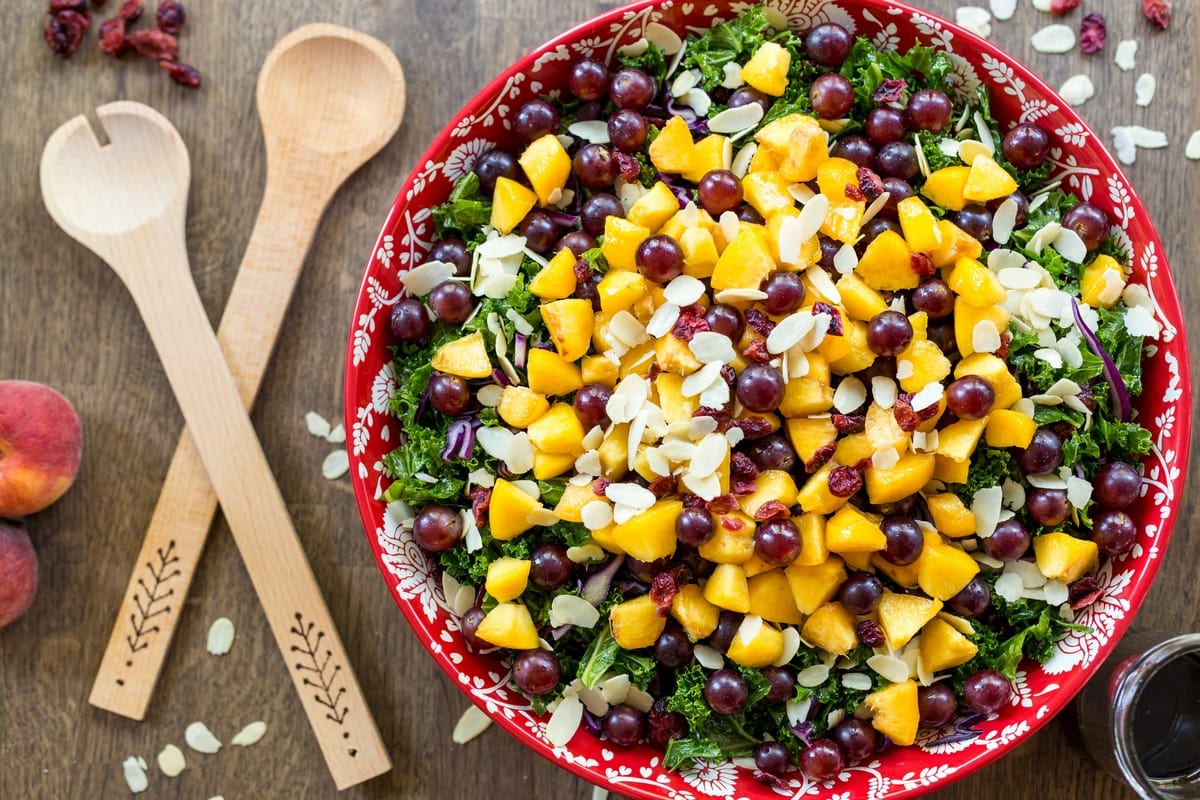 Fruity kale salad with peaches, grapes and almonds. With vegan balsamico dressing.