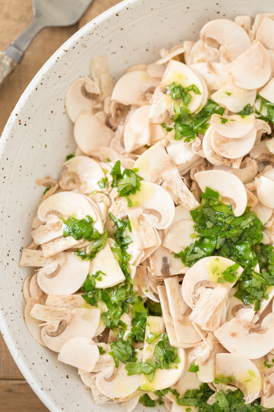 Cilantro lime dressing poured over thinly sliced mushrooms to make raw mushroom salad.