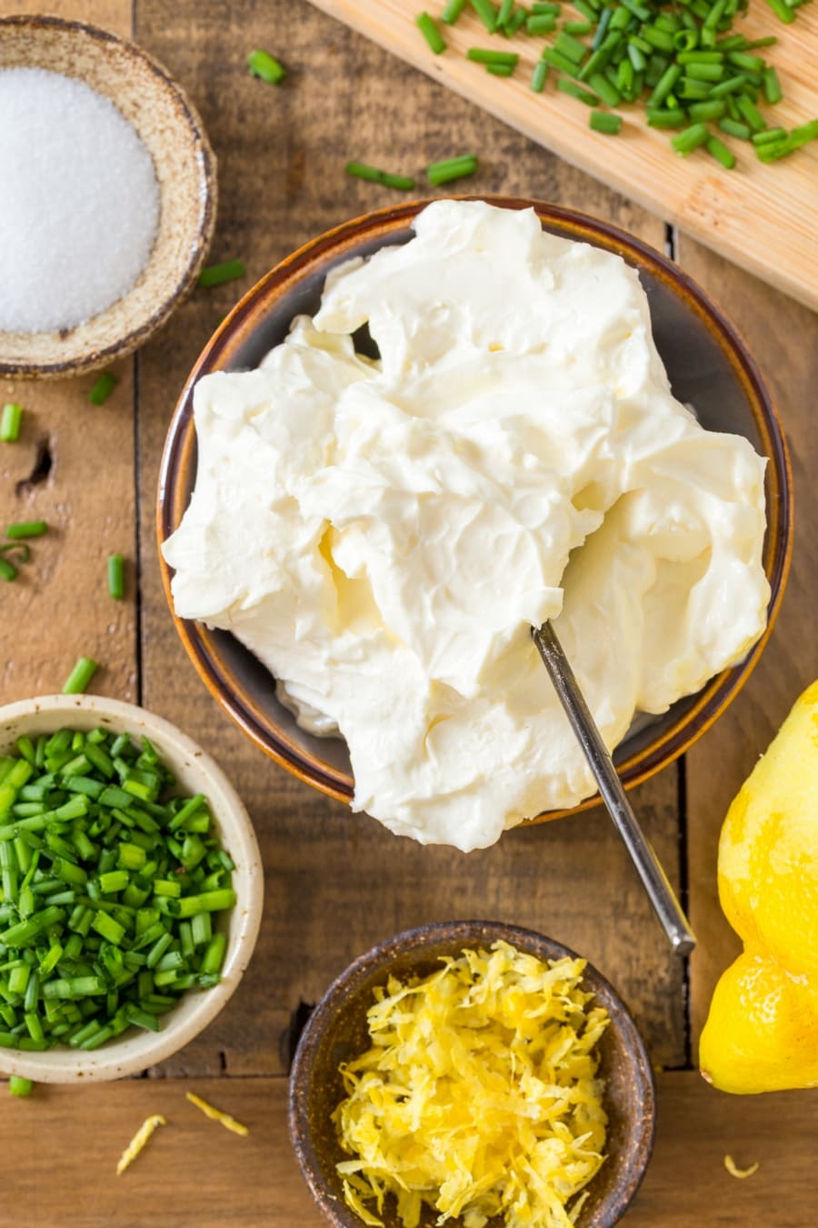 Mascarpone in larger bowl, smaller bowls with chives, lemon zest and salt.